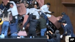 In this image made from video, lawmakers from the Democratic Progressive Party use chairs to block the entrance as members of the Kuomintang party try to break into the Legislature in Taipei, Taiwan, on Dec. 20, 2024. (EBC via AP)