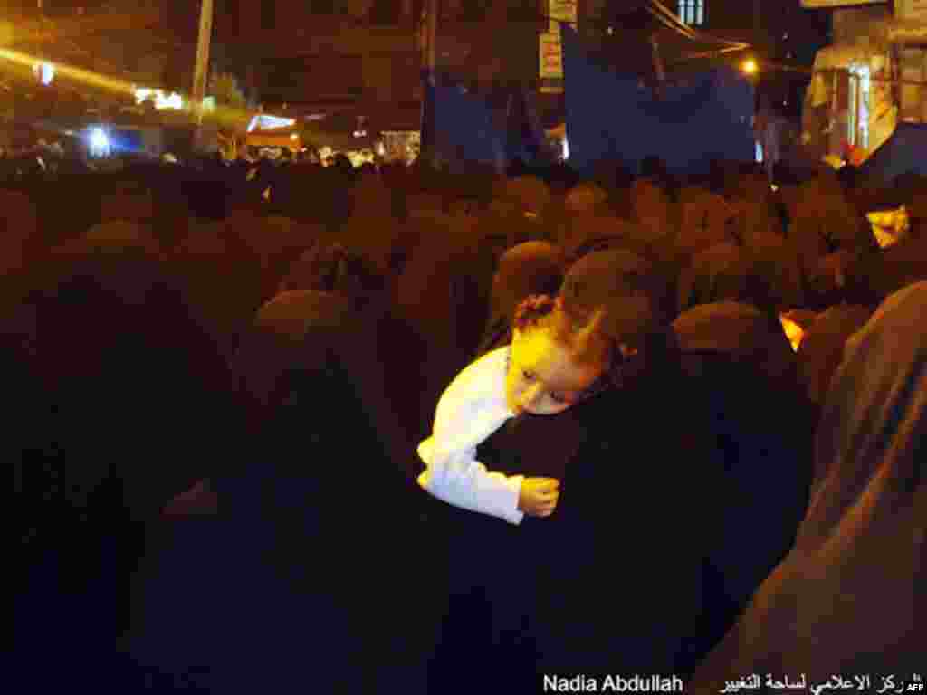 A woman praying at night during Ramadan holds a little girl. (Photo - Nadia Abdullah)