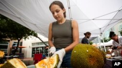 Sara Diaz, from LNB Groves, cuts a jackfruit at the Monday night green market in downtown Miami, Monday, June 8, 2015. (AP Photo/J Pat Carter)