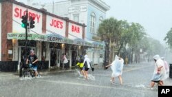 Determined visitors head for Sloppy Joe's Bar while crossing a flooded Duval Street as heavy winds and rain pass over Key West, Fla., July 6, 2021.