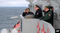 FILE -Russian President Vladimir Putin, left, and Russian navy officials watch a navy exercise from from a missile cruiser in the Black Sea, Crimea, Jan. 9, 2020.