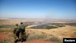 FILE - Israeli soldiers look at the Syrian side of the Israel-Syria border on the Israeli-occupied Golan Heights, Israel, July 7, 2018.