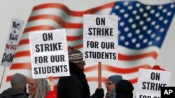 Teachers carry signs as they walk a picket line outside a Denver high school, Feb. 11, 2019.