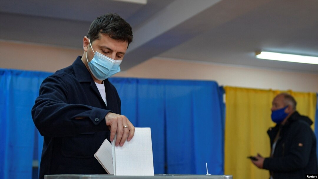 Presiden Ukraina Volodymyr Zelenskiy dengan mengenakan masker memasukkan surat suara untuk pemilu di tengah virus corona (Covid-19) di Kyiv, Ukraina, 25 Oktober 2020. (Foto: Reuters)