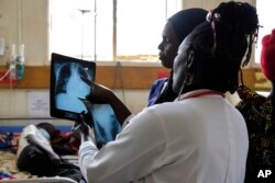 FILE—Julian Abeso looks at a sickle cell patient's x-ray image at the Mbale Regional Referral Hospital, Uganda, April. 24, 2024