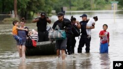 FILE - Residents walk through floodwaters after being evacuated from their flooded apartment complex, in Houston.