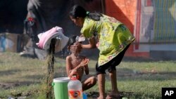 Seorang ibu memandikan bocah di tempat penampungan sementara di Palu, Central Sulawesi, 4 Oktober 2018. 