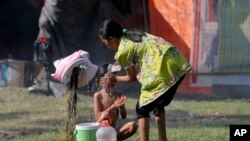 Seorang wanita memandikan anaknya di tempat penampungan sementara di Palu, Sulawesi Tengah, 4 Oktober 2018 (foto: AP Photo/Tatan Syuflana)