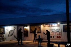People stand around the Little A'Le'Inn during an event inspired by the "Storm Area 51," Sept. 19, 2019, in Rachel, Nevada.