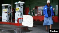 A woman walks past a "No Petrol" sign at a fuel station in Harare, Zimbabwe, Oct. 9, 2018. 