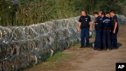 Hungarian police inspect a barbed wire fence on the border with Serbia, in Roszke, Hungary, Aug. 29, 2015. 