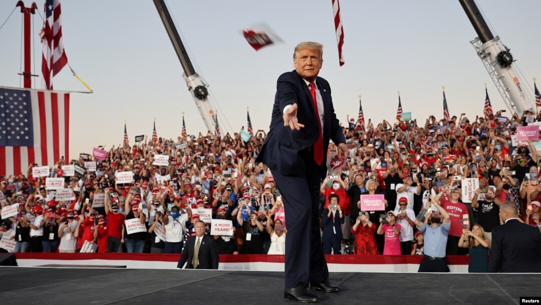 Presiden AS Donald Trump membuang maskernya ke arah pendukungnya dalam kampanye di Sanford, Florida. 