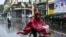 FILE - A woman in a poncho rides a bicycle during heavy rainfall in Hanoi, Oct. 14, 2020, as tropical storm Nangka made landfall in north-central Vietnam. 