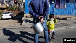 Un hombre espera junto a su hijo para recibir una ración de comida de parte de la organización Olla Común en Valparaíso, Chile, el 13 de Julio de 2020.