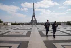 Police officers check their phones as they walk on Trocadero plaza during a nationwide confinement to counter the new coronavirus, in Paris, April 2, 2020.