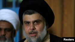 FILE - Iraqi Shi'ite cleric Moqtada al-Sadr speaks during a news conference with Leader of the Conquest Coalition and the Iran-backed Shi'ite militia Badr Organisation Hadi al-Amiri, in Najaf, June 12, 2018.