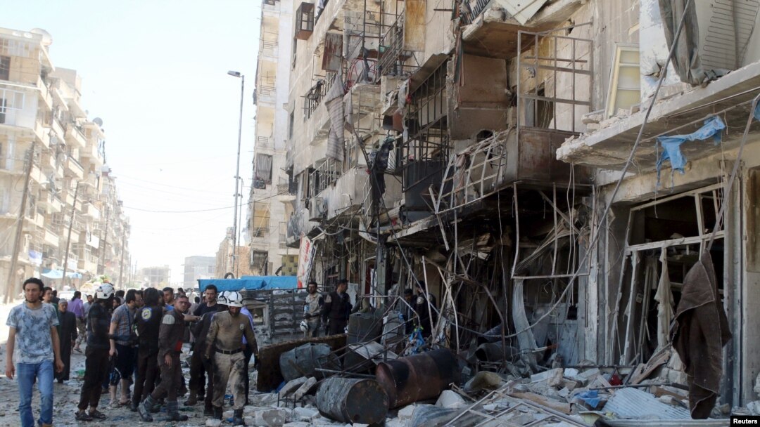 Warga dan anggota keamanan sipil memeriksa sebuah bangunan yang hancur pasca serangan udara di wilayah Tariq al-Bab, Aleppo, Suriah (23/4).