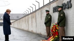 FILE - German Chancellor Angela Merkel observes a moment of silence as she lays a wreath during a ceremony at the memorial in the former Nazi concentration camp in Dachau, near Munich, May 3, 2015, to mark the 70th anniversary of the liberation of the camp.