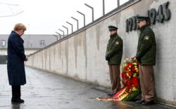 FILE - German Chancellor Angela Merkel observes a moment of silence as she lays a wreath at the memorial in the former German Nazi concentration camp in Dachau to mark the 70th anniversary of the liberation of the camp.