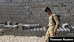 FILE - An Iraqi soldier scans the ground for weapons during a raid in Basra, Iraq, Sept. 8, 2020. 