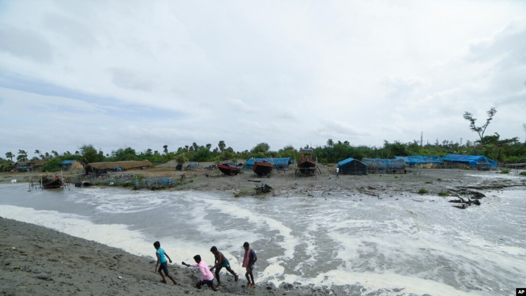 Village men walk past as sea water gushes in after breaking an embankment on the Bay of Bengal coast in South 24 parganas, West Bengal state, India, May 25, 2021.