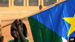 A girl holds a South Sudan flag on January 30 during the announcement of the preliminary results of voting on independence