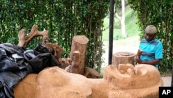 FILE - Lilian Nabulime carving wood into a wooden sculpture piece at her workshop in Kyanja, a suburb in Kampala City, November 29, 2023.