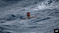A man treads water and awaits rescue crews approximately 32 miles southeast of Key West, Fla., on July 6, 2021. The U.S. Coast Guard and a good Samaritan rescued 13 people after their boat capsized off of Key West as Tropical Storm Elsa approached.