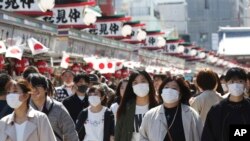Visitors wearing face masks walk through Nakamise alley at Asakusa in Tokyo, March 20, 2020. 