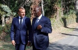 French President Emmanuel Macron, left, talks with Ivory Coast's President Alassane Ouattara during a ceremony marking the 75th anniversary of the WWII Allied landings in Provence, in Saint-Raphael, southern France, Aug. 15, 2019.