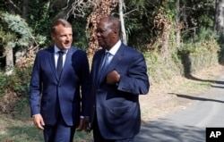 French President Emmanuel Macron, left, talks with Ivory Coast's President Alassane Ouattara during a ceremony marking the 75th anniversary of the WWII Allied landings in Provence, in Saint-Raphael, southern France, Aug. 15, 2019.