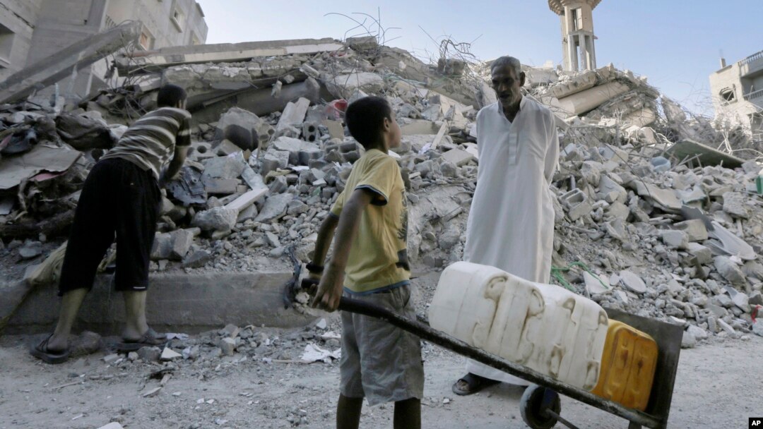 Seorang pria Palestina berbicara dengan seorang anak di antara reruntuhan Masjid al-Qassam, di kamp pengungsi Nusseirat, Jalur Gaza (10/8).