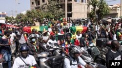 FILE — Civil society groups and political groups hold placards and Senegalese national flags as they march calling on authorities respect the election date, in Dakar, on February 17, 2024.