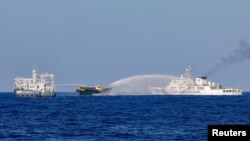 FILE - Chinese Coast Guard vessels fire water cannons towards a Philippine resupply vessel Unaizah May 4 on its way to a resupply mission at Second Thomas Shoal in the South China Sea, March 5, 2024.