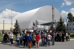 Visitors stand outside the New Safe Confinement structure over the old sarcophagus covering the damaged fourth reactor at the Chernobyl Nuclear Power Plant, in Chernobyl, Ukraine, June 2, 2019.