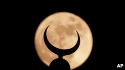 A supermoon is seen through a crescent of a minaret of Faisal mosque in Islamabad, Pakistan, Dec. 13, 2016.