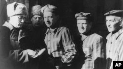 FILE- In this file photo dated January 1945, three prisoners, right, talk with Soviet soldiers after the Nazi concentration camp Auschwitz, in Poland, was liberated.