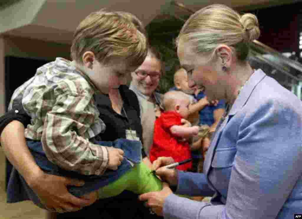 US Secretary of State Hillary Clinton signs the cast of 3-year-old Toby Webster-Main as as she meets with employees and their families in Yangon, Myanmar, Friday, Dec. 2, 2011. (AP Photo/Saul Loeb, Pool)