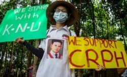 A supporter of the Karen National Union (KNU) holds a sign supporting the Committee for Representing Pyidaungsu Hluttaw (CRPH), in this handout photo from the KNU Doo Pla Ya District taken and released to AFP on April 2, 2021.