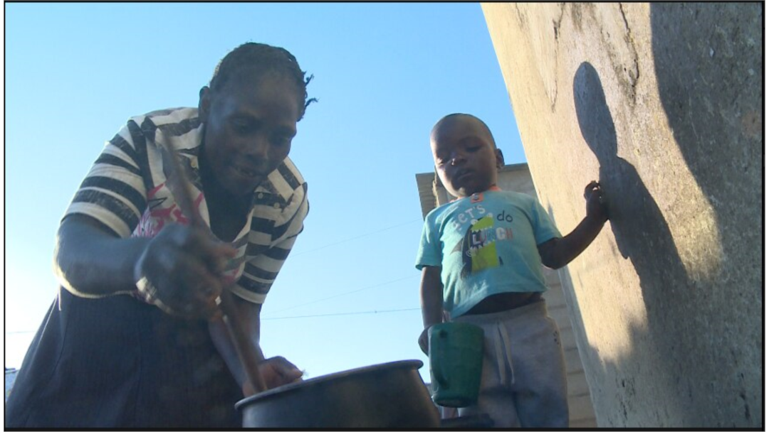 A child waits as Plaxedes Chibura prepares sadza — Zimbabwe’s staple food made of corn — in Epworth, Zimbabwe, July 18, 2019. (Columbus Mavhunga/VOA)