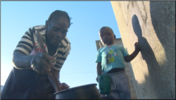 A child waits as Plaxedes Chibura prepares sadza — Zimbabwe’s staple food made of corn — in Epworth, Zimbabwe, July 18, 2019. (Columbus Mavhunga/VOA)