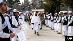 Sejumlah siswa memegang bendera Taliban ketika menyambut otoritas yang datang berkunjung Sekolah Menengah Amani di Kabul pada 20 Maret 2024 dalam upacara peringatan tahun ajaran baru. (Foto: AFP/Wakil Kohsar)