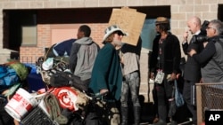 An unidentified man drags his belongings away during a sweep of homeless people who were living on the walks surrounding a shelter November 15 near the baseball stadium in downtown Denver. (AP Photo/David Zalubowski)