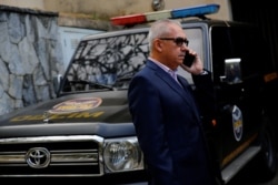 Joel Garcia, lawyer of Juan Marquez, uncle of Venezuela's opposition leader Juan Guaido, talks on the phone in front of a Directorate General of Military Counterintelligence vehicle in Caracas, Venezuela, Feb.20, 2020.