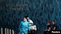 Health workers move a patient wearing a face mask at the at NYU Langone Hospital, during the outbreak of the coronavirus disease (COVID-19) in the Manhattan borough of New York City, New York, May 3, 2020.