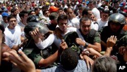 Opposition leader Leopoldo Lopez, dressed in white and holding up a flower stem, is taken into custody by Bolivarian National Guards, in Caracas, Venezuela, Feb 18, 2014. 