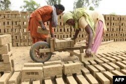 بھارت میں اینٹوں کے ایک بھٹے میں خواتین کام کر رہی ہیں۔ فائل فوٹو