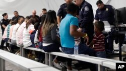 FILE - Migrants who are applying for asylum in the United States go through a processing area at a new tent courtroom at the Migration Protection Protocols Immigration Hearing Facility, in Laredo, Texas, Sept. 17, 2019. 
