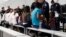 FILE - Migrants who are applying for asylum in the United States go through a processing area at a new tent courtroom at the Migration Protection Protocols Immigration Hearing Facility, in Laredo, Texas, Sept. 17, 2019. 