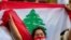 FILE - An anti-government protester shouts slogans while wearing a mask with the colors of the Lebanese flag in Beirut, Lebanon, July 2, 2020. 